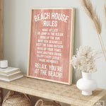 A Beach House Rules Sign, Painted Wood in Coral, sits framed on a woven console, adding charming coastal decor to the room.