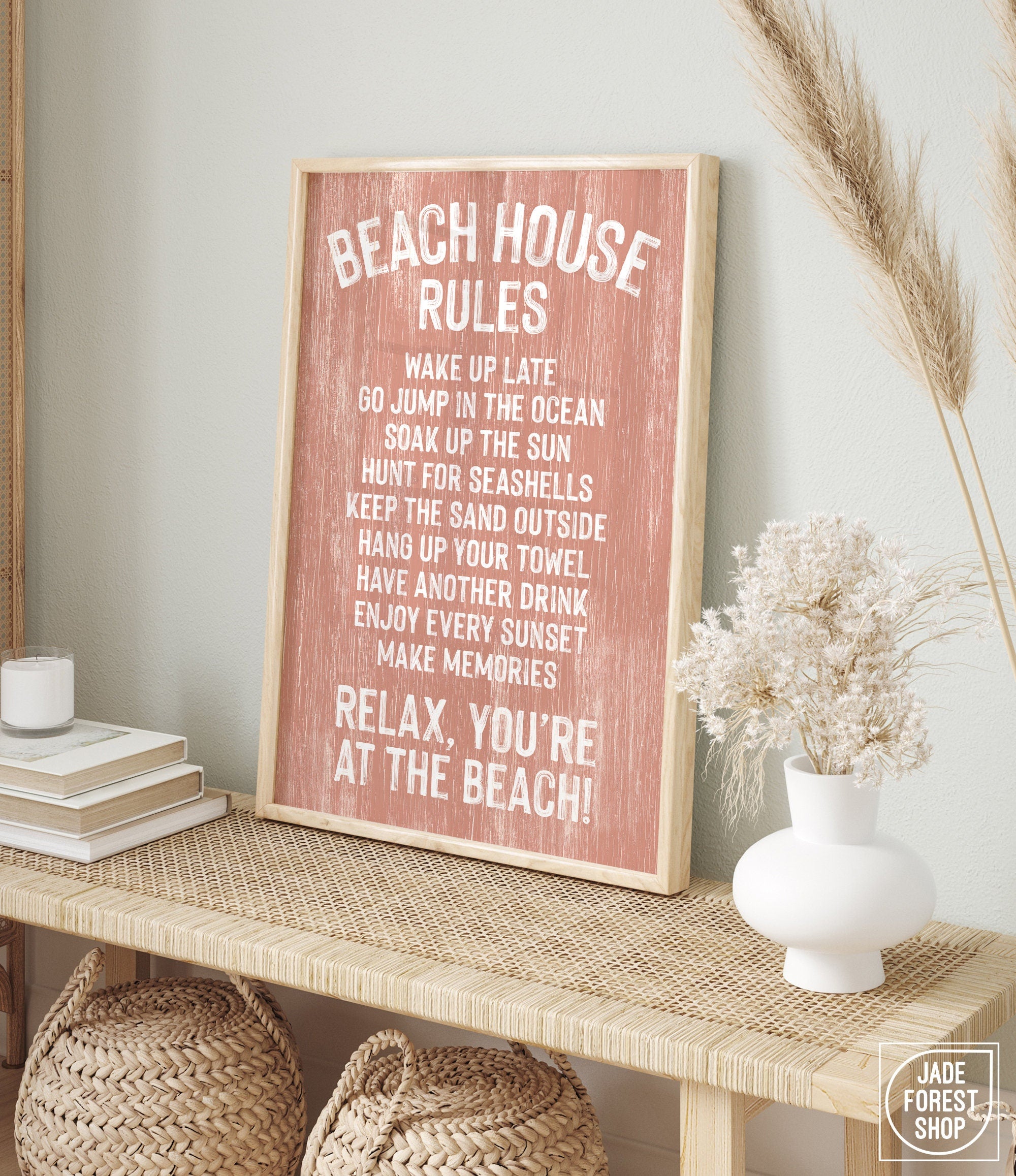 A Beach House Rules Sign, Painted Wood in Coral, sits framed on a woven console, adding charming coastal decor to the room.