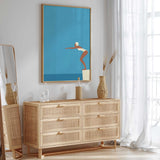 a modern, minimalist bedroom with a large mirror, a wooden dresser, and a framed artwork depicting a woman in a swimming pose.