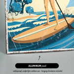 A woman is standing on a surfboard and paddling through the waves, with a beach and trees in the background.
