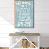 A Beach House Rules Sign in painted wood, in the Tide color, hangs above a wooden console table with decorative items and baskets, creating charming beach house wall decor.