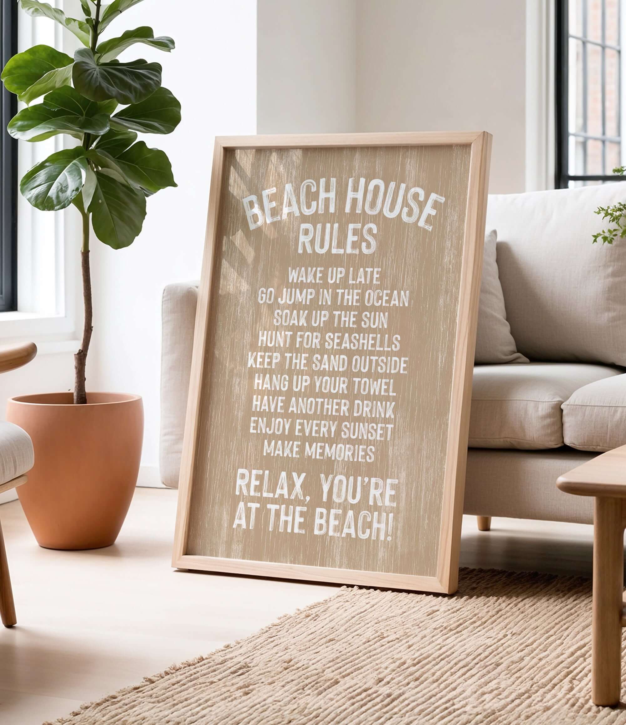 A wooden sign with white text that reads "BEACH HOUSE RULES" is displayed in a living room, with a potted plant and a couch visible in the background.