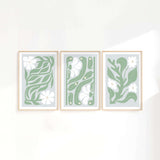 three green and white paintings hanging on a wall