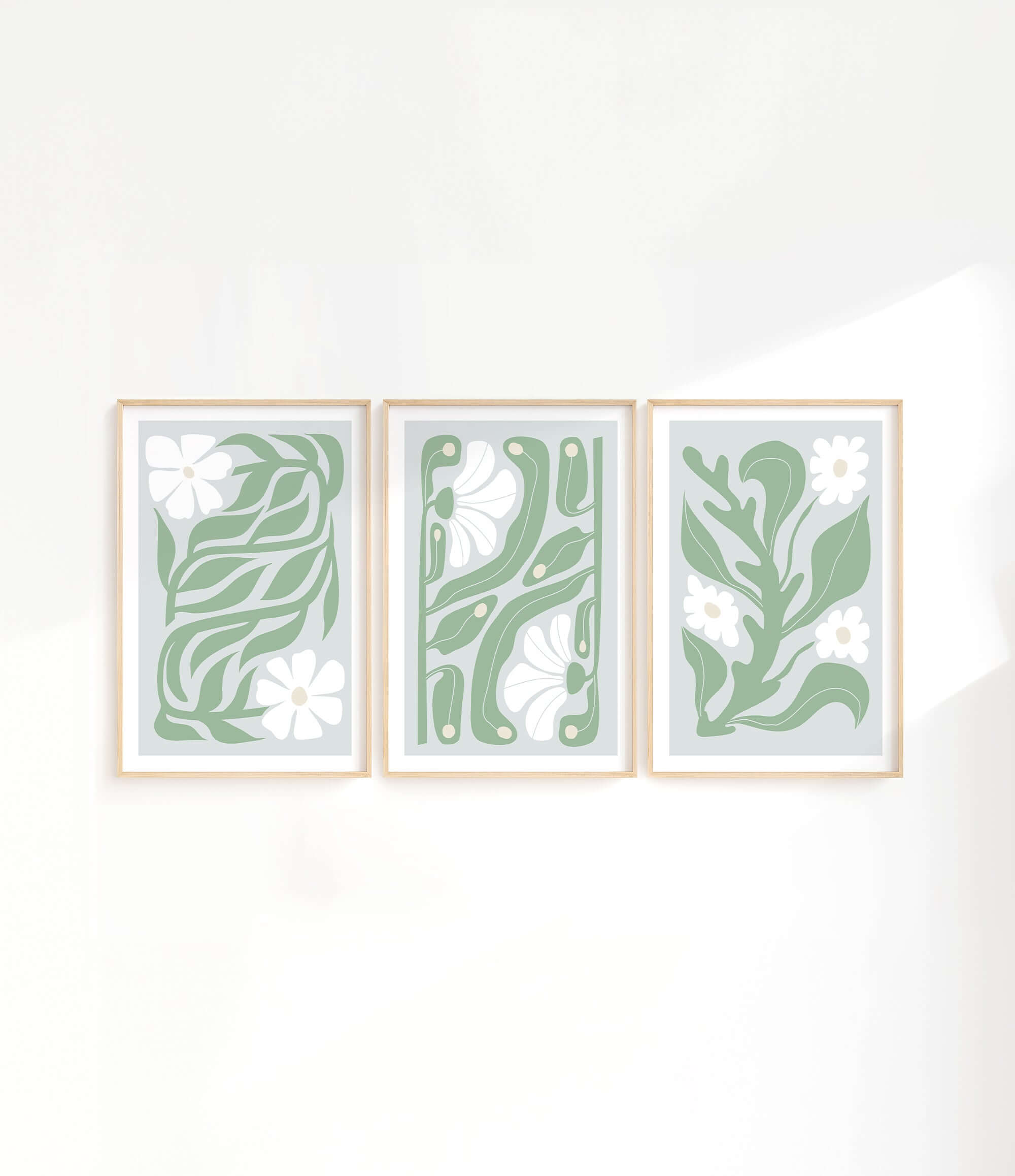 three green and white paintings hanging on a wall