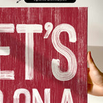 a hand holding a red poster with white lettering