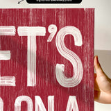 a hand holding a red poster with white lettering