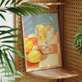 a framed painting of a glass of lemonade with lemon slices, set against a checkered tablecloth.