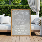 a sign that reads "LAKESHOUSE RULES" in a rustic wooden frame, placed on a wooden deck with a white couch and a white curtain in the background.