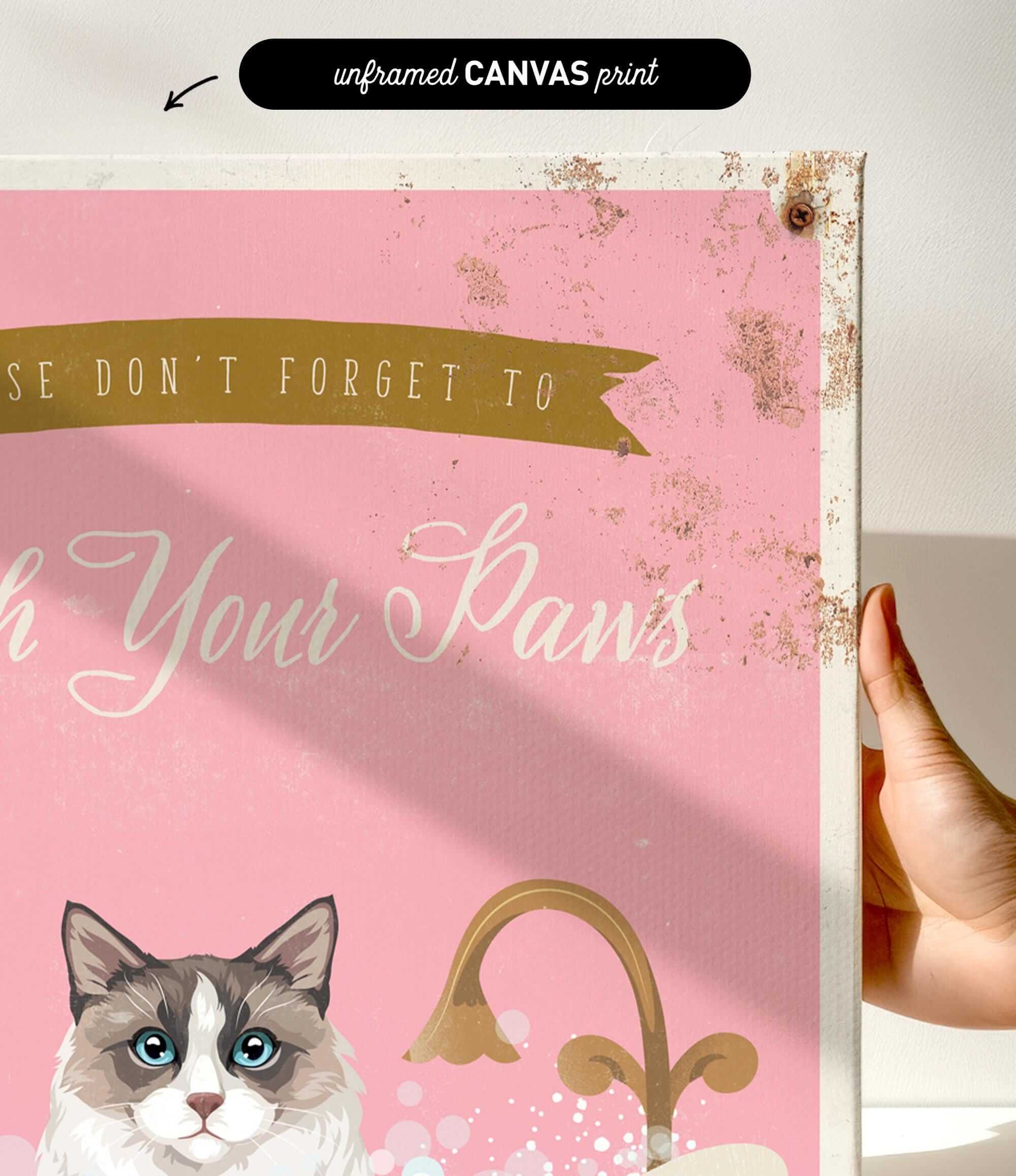 a hand holding a framed canvas print with a cat illustration and text.