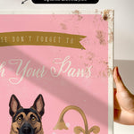 a hand holding a framed canvas print with a dog illustration and text.