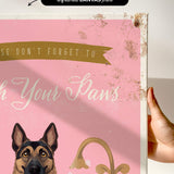 a hand holding a framed canvas print with a dog illustration and text.