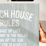 a hand holding a canvas print with the text "CHEACH HOUSE RULES" written on it.