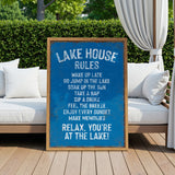A blue sign with white text is displayed in front of a wooden deck with white cushions, and a white curtain is visible in the background.