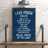 A blue sign with white text that reads "LAKESHOUSE RULES" is displayed on a wooden shelf against a white brick wall.