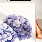 a close-up of a white canvas with a vibrant purple flower depicted on it.