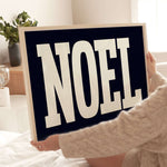 a woman holding up a sign that says noel