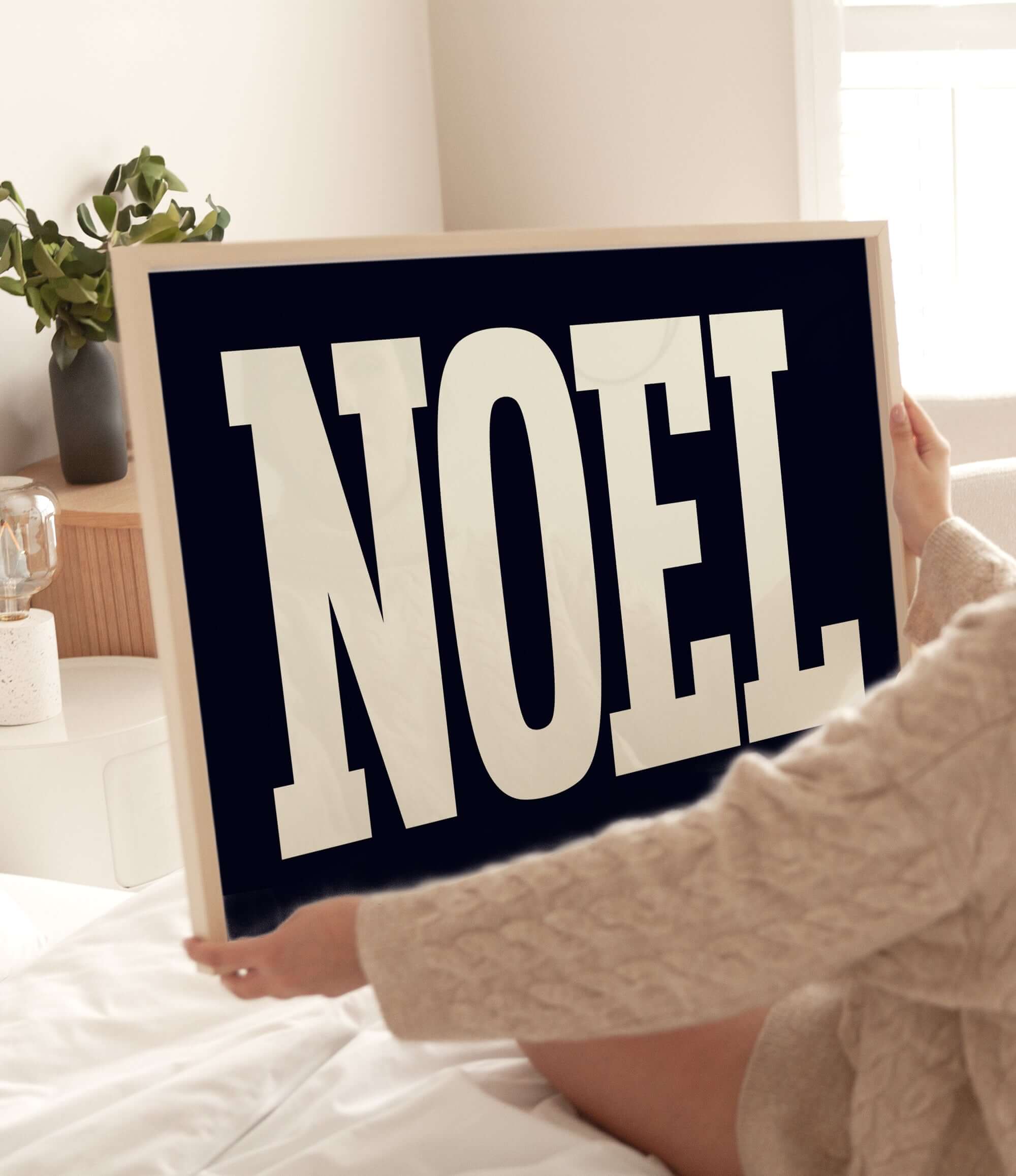 a woman holding up a sign that says noel