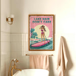 a bathroom with a framed poster of a woman paddleboarding on a lake, along with a towel rack and a bathtub.