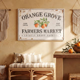 a rustic interior with a large sign for Orange Grove Farmers Market hanging on the wall. The sign displays the text "Orange Grove" and "Farm Fresh", indicating the name and nature of the market. The room also includes a bench, a woven basket, and a bowl of oranges, creating a cozy and inviting atmosphere.