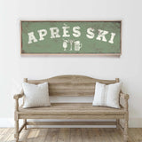a wooden bench with two striped pillows, and above it is a framed sign with the text "APRÈS SKI" in white letters.