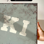 a close-up view of a textured, weathered surface with a large, bold, white letter "K" prominently displayed.