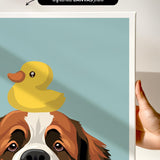 A hand is holding a framed print featuring a cartoon image of a dog with a yellow rubber duck on its head.