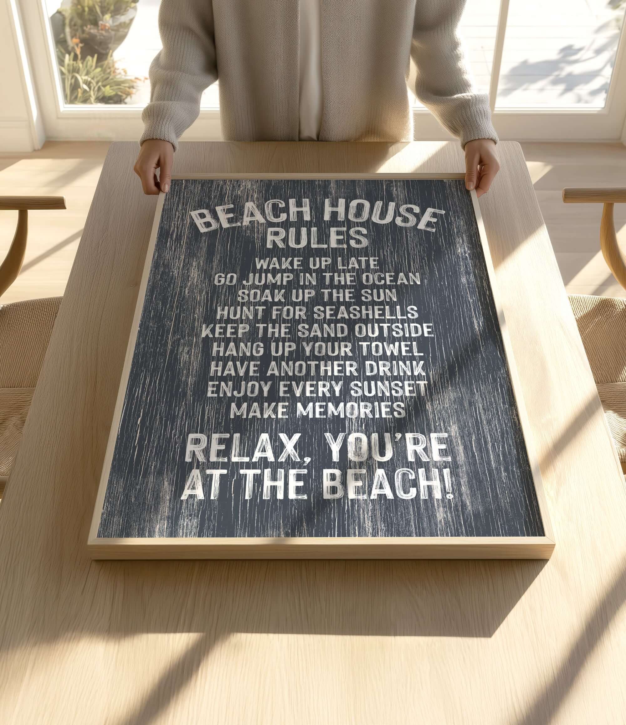 A person is holding up a sign with the text "BEACH HOUSE RULES" written on it, which appears to be a beach-themed sign with instructions for beachgoers.