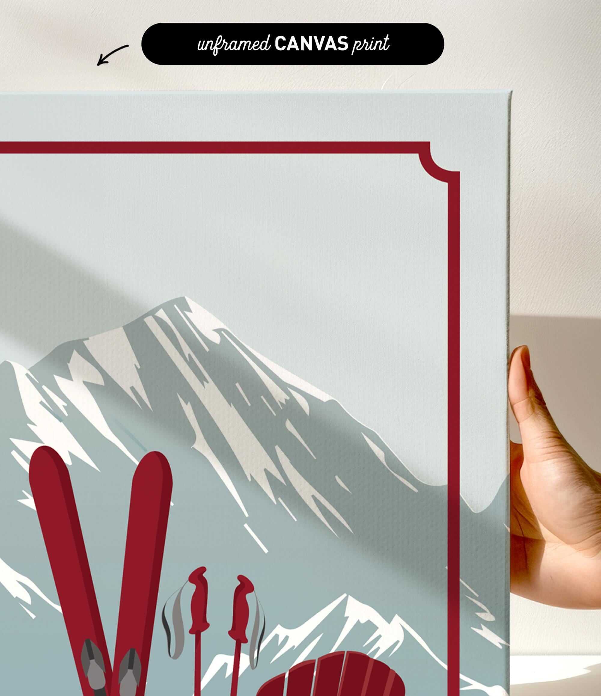 a hand holding a framed print of a mountain landscape with skis and ski poles.