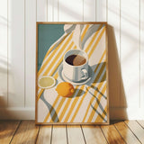 A framed illustration of a cup of coffee, a lemon slice, and a striped cloth on a wooden floor.