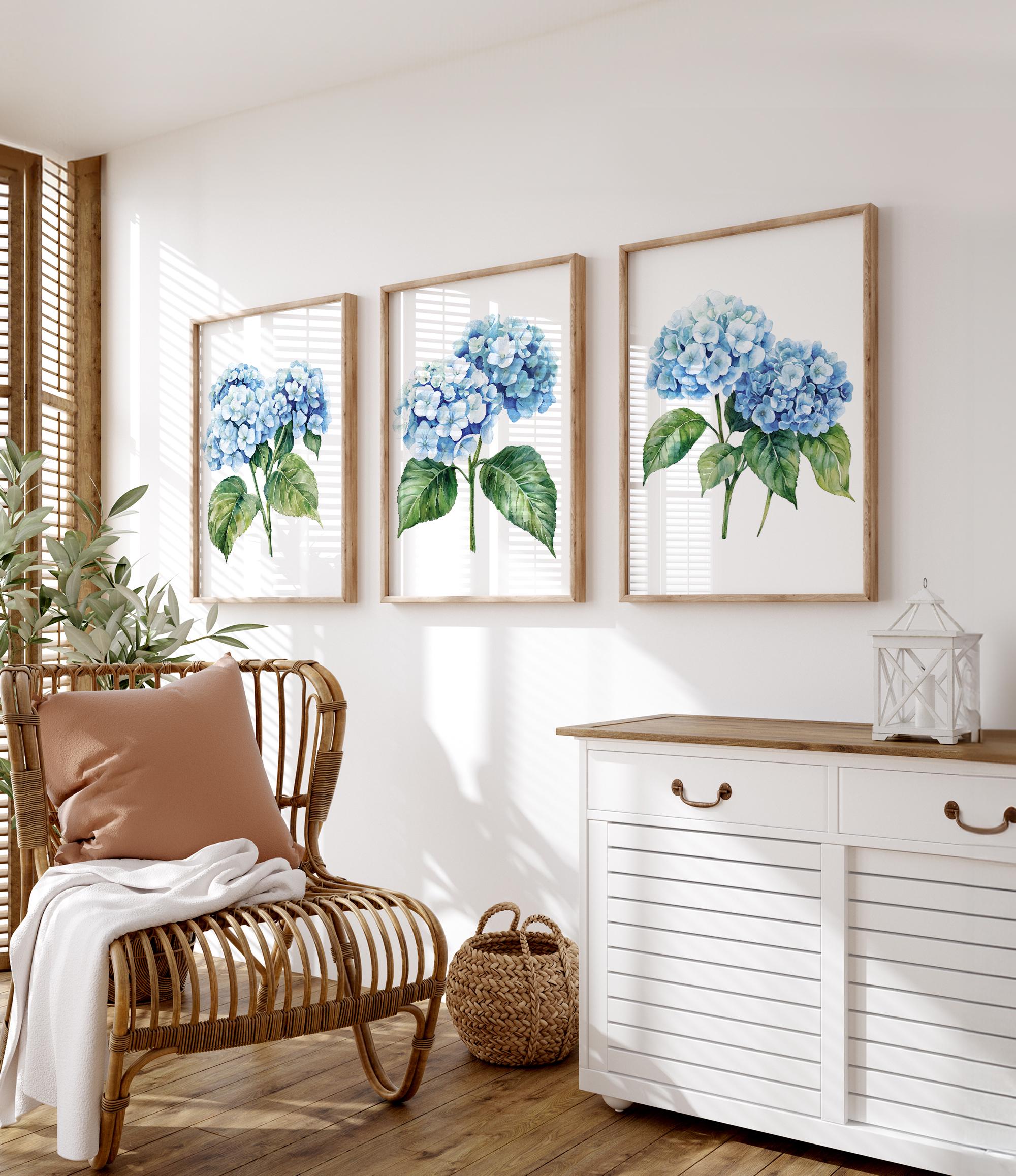 a cozy living room with a wicker chair, a white dresser, and three framed watercolor paintings of blue hydrangeas hanging on the wall.