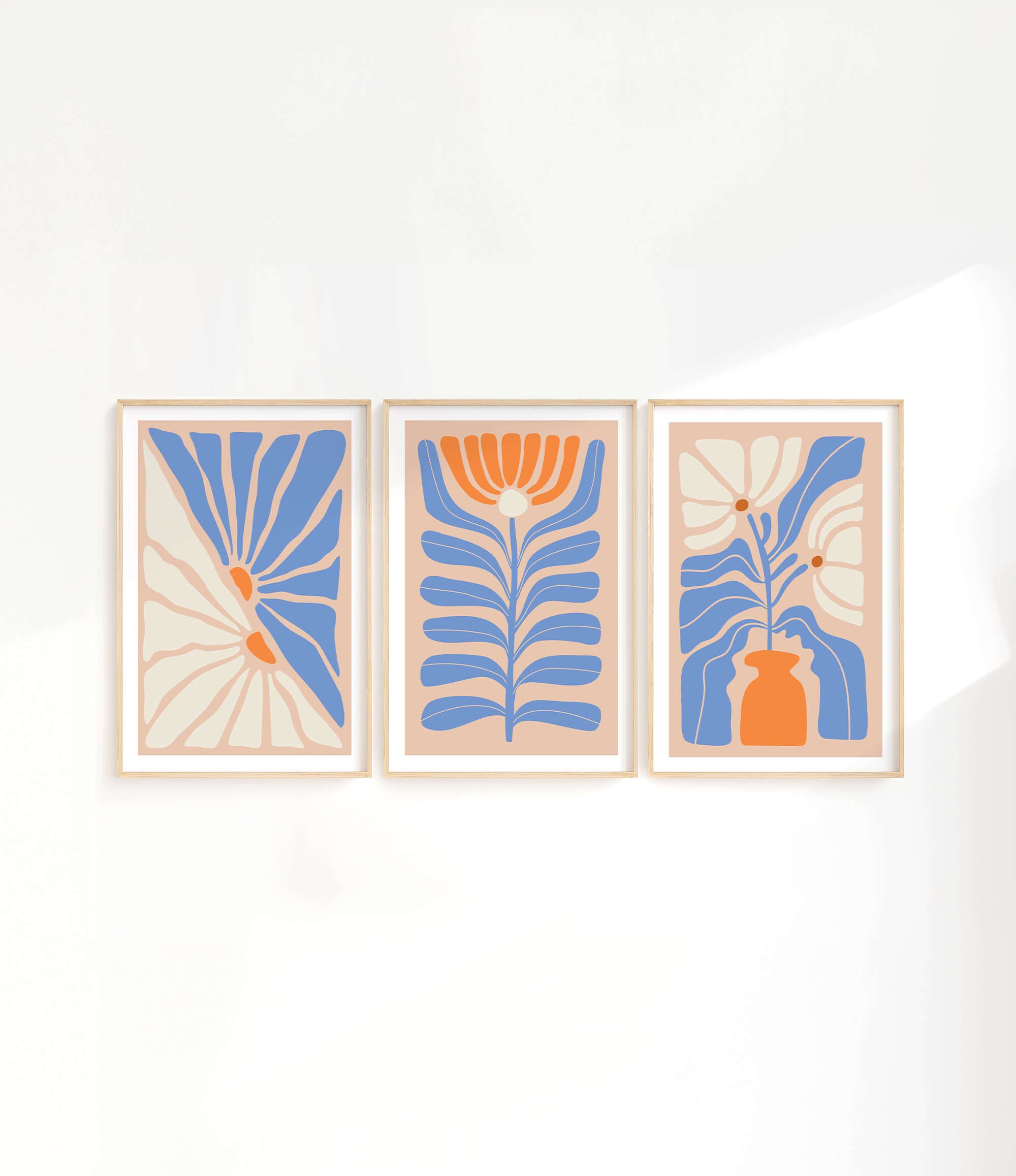 three paintings of blue and orange flowers on a white wall