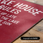 The image is a close-up of a red sign with white text, placed on a wooden surface.