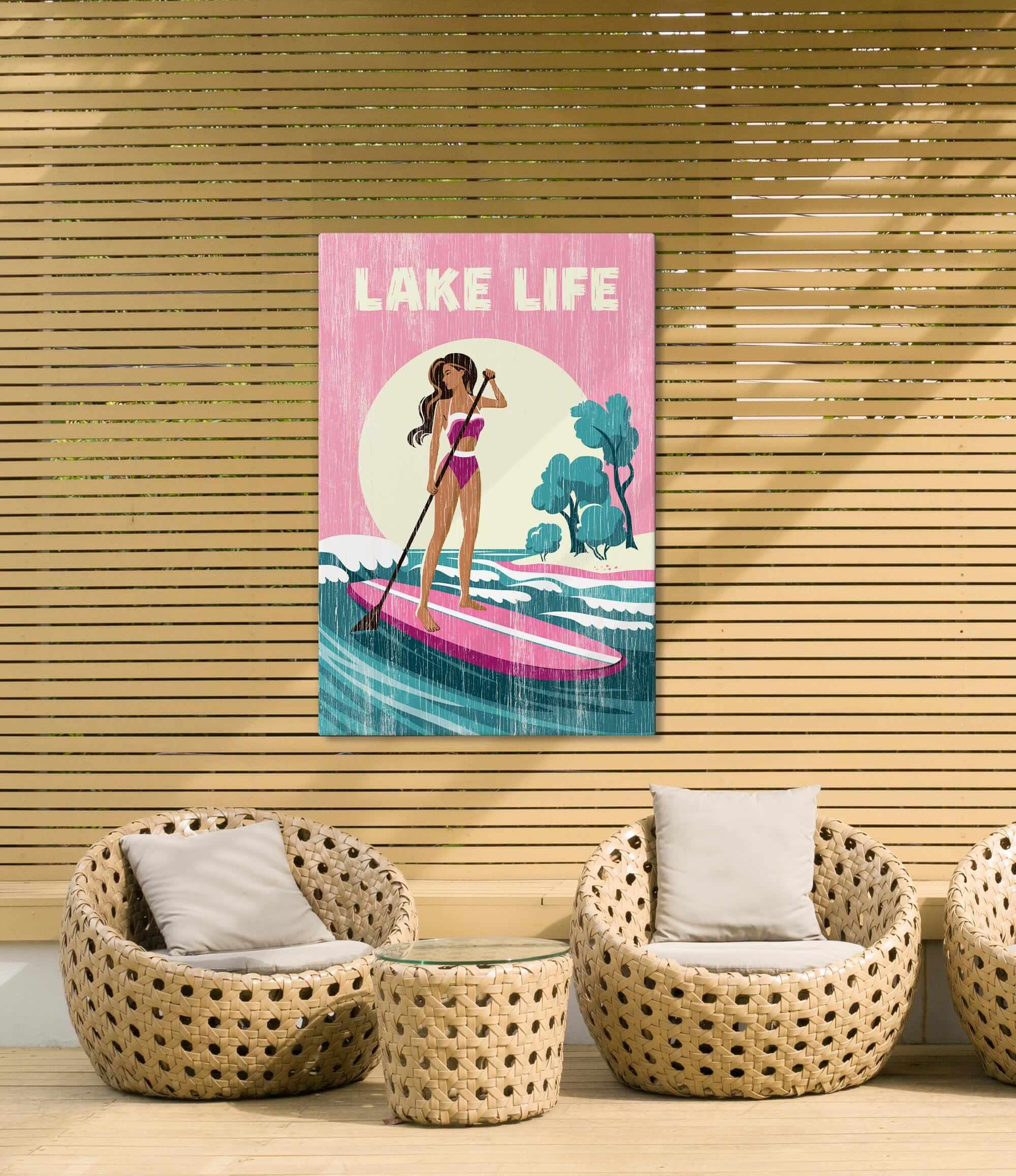 a woman paddleboarding on a surfboard, with a sign above her that says "LAKELife".