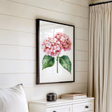 a framed painting of pink hydrangeas hanging on a white wall above a white dresser with a stack of books on top.