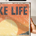 a person holding up a poster that says take life