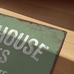 a close-up view of a green sign with white text, resting on a wooden surface.