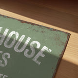 a close-up view of a green sign with white text, resting on a wooden surface.