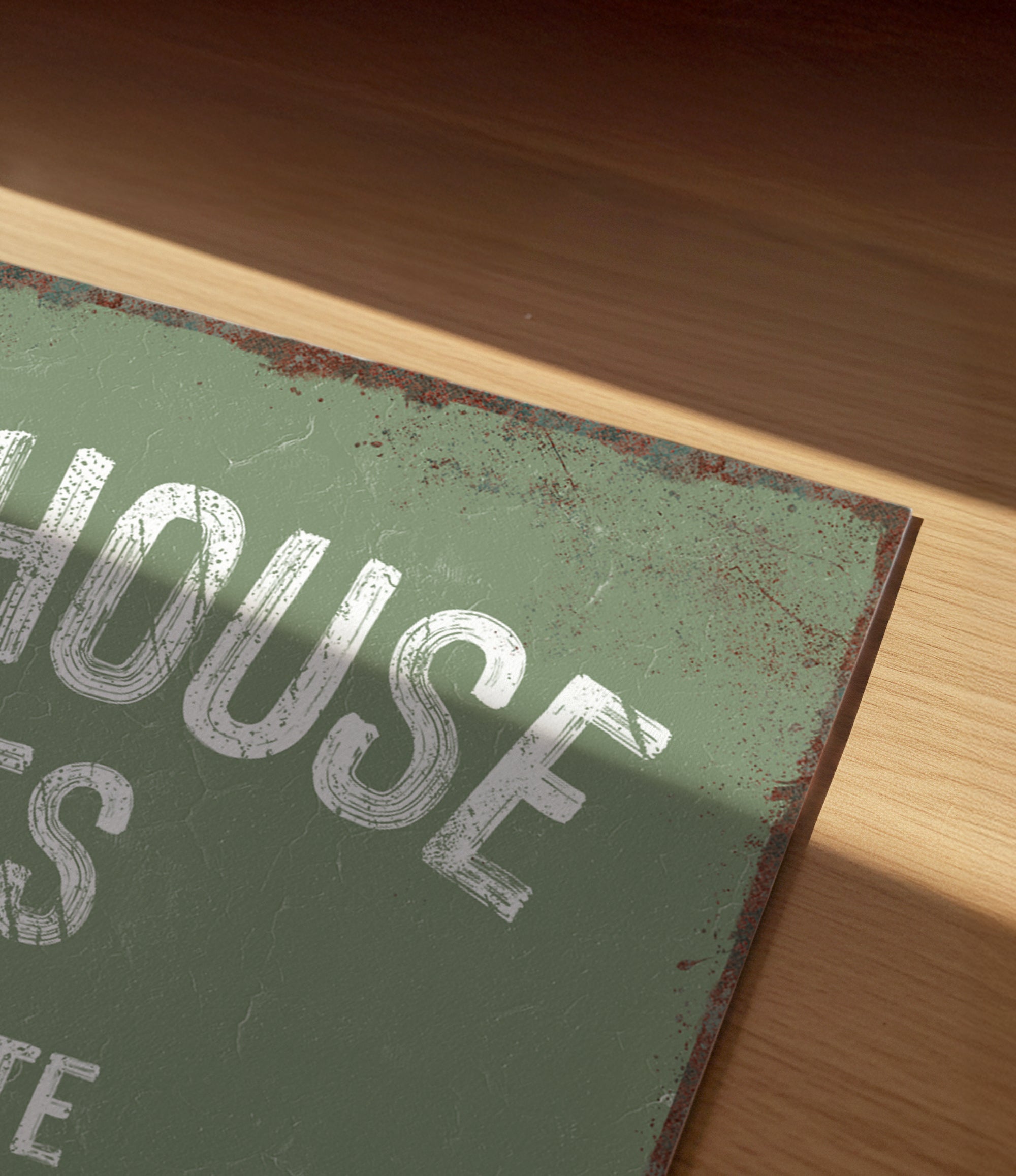 a close-up view of a green sign with white text, resting on a wooden surface.
