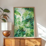 a wooden cabinet with a lamp on top, and a framed painting of lush green palm leaves hanging on the wall above the cabinet.