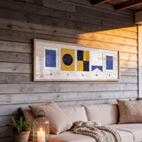 a cozy living space with a wooden wall, a beige sofa, and a framed artwork hanging above it. The artwork displays the word "SILAS" in a creative and artistic manner.