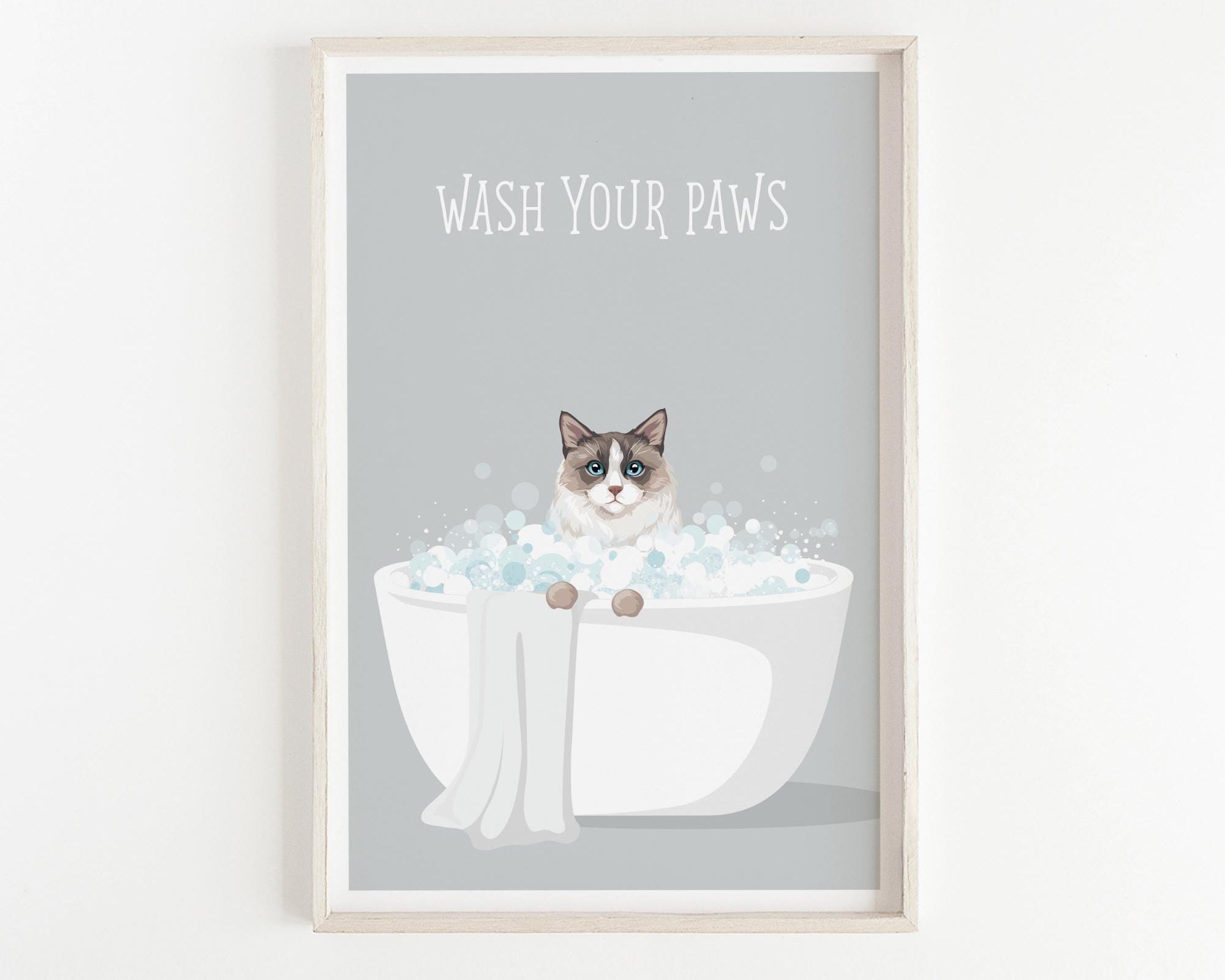A framed poster with a cat sitting in a bathtub filled with bubbles, with the text "WASH YOUR PAWS" displayed above it.