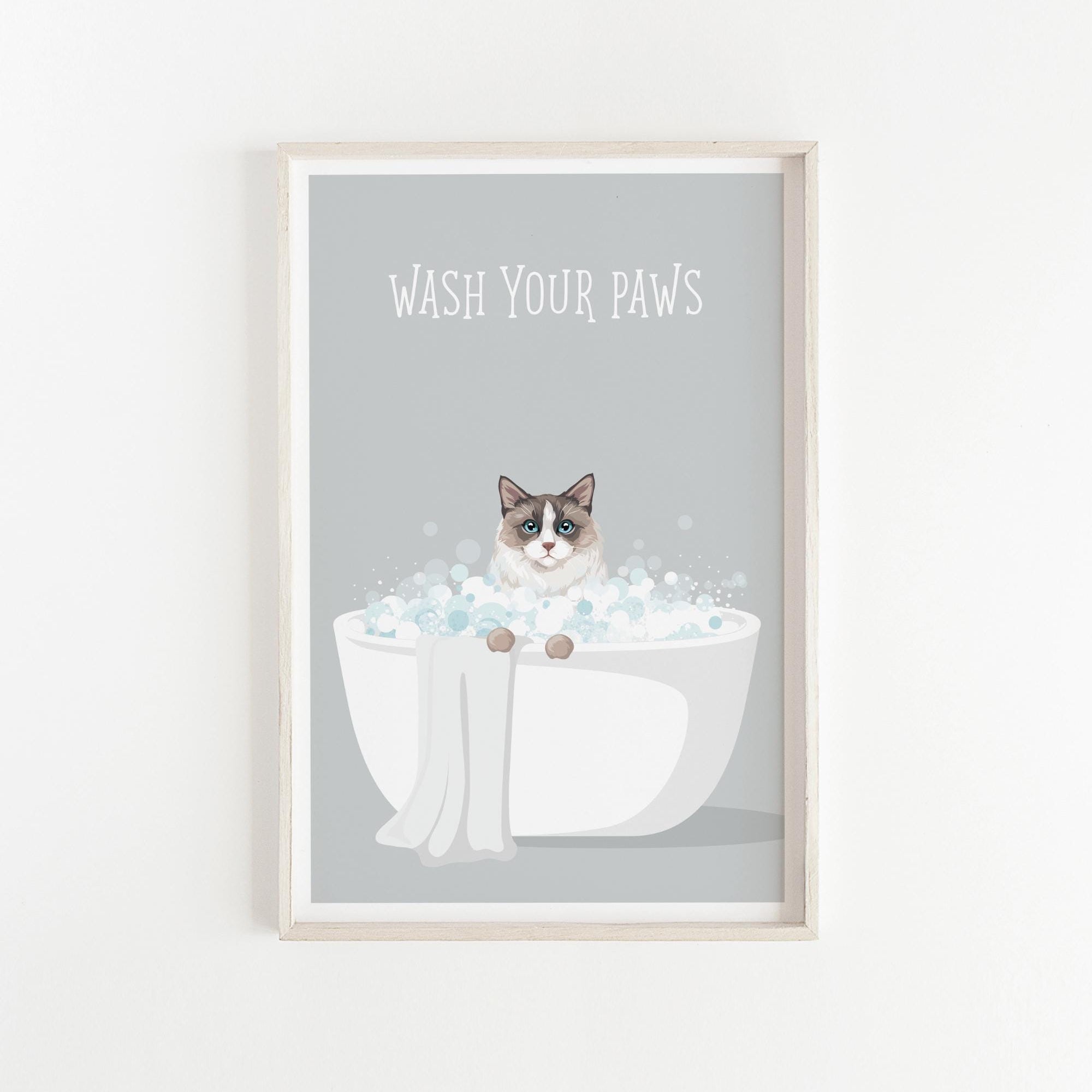 A framed poster with a cat sitting in a bathtub filled with bubbles, with the text "WASH YOUR PAWS" displayed above it.