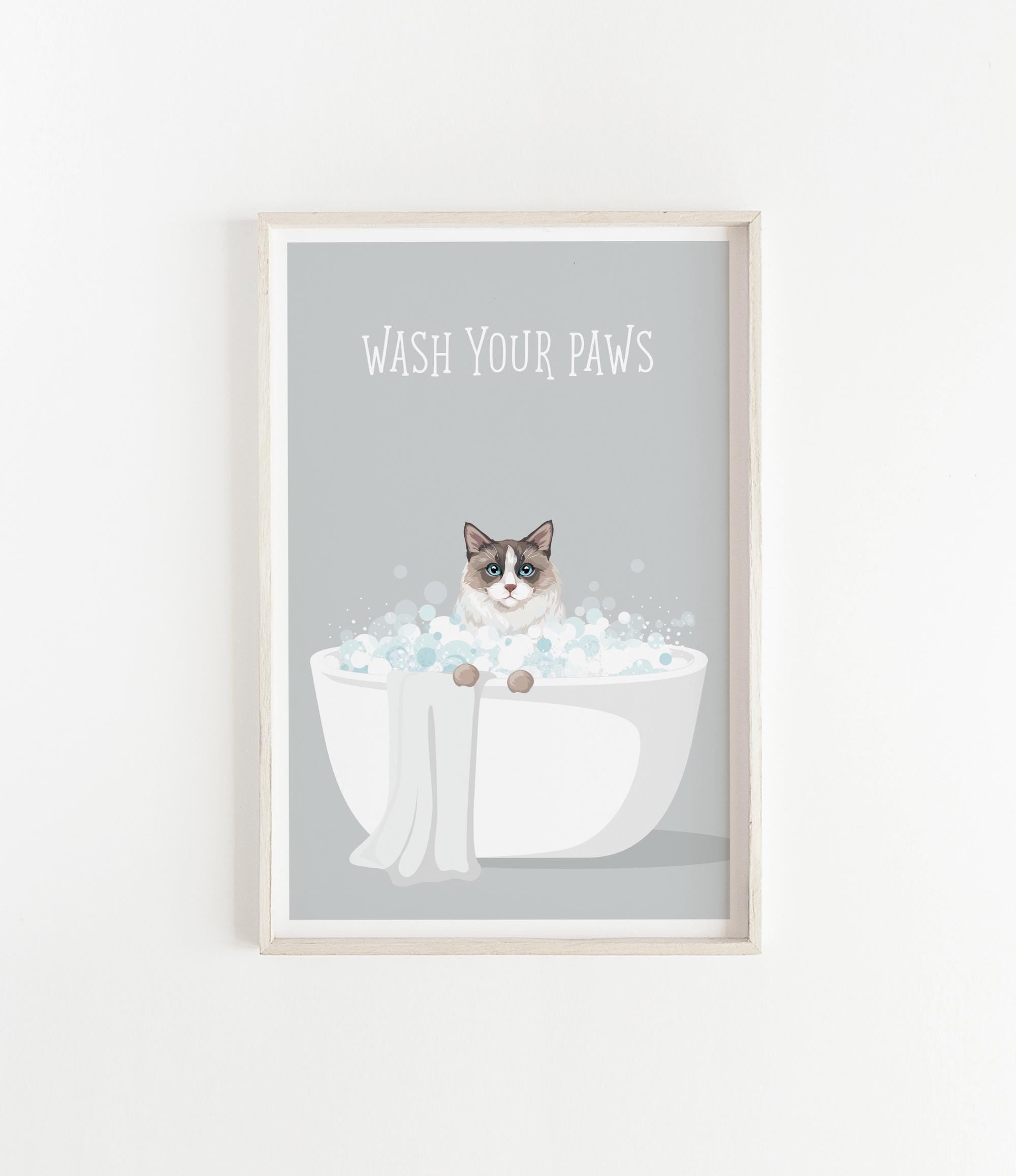 A framed poster with a cat sitting in a bathtub filled with bubbles, with the text "WASH YOUR PAWS" displayed above it.