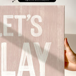 a person holding a sign that says let&#39;s play