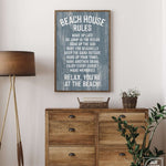 A Beach House Rules Sign in painted wood, harbor blue, hangs above a wooden dresser with a plant and basket, bringing cozy beach house decor to the room.