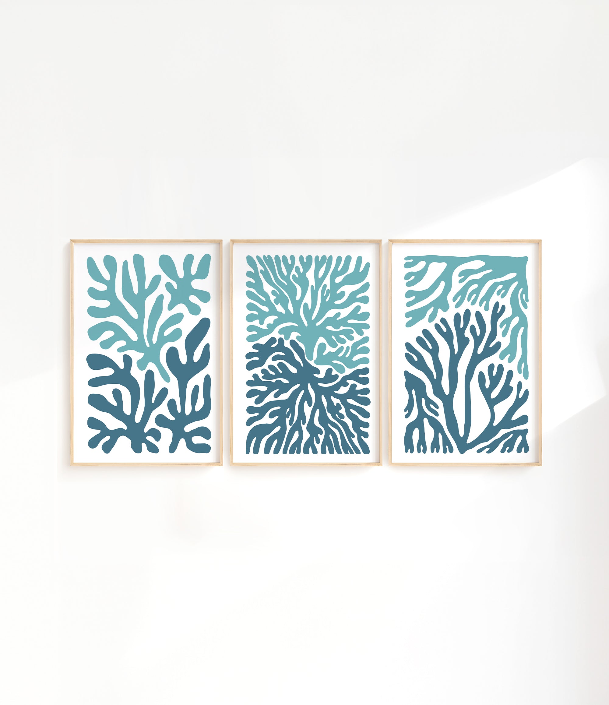 three paintings of blue corals on a white wall