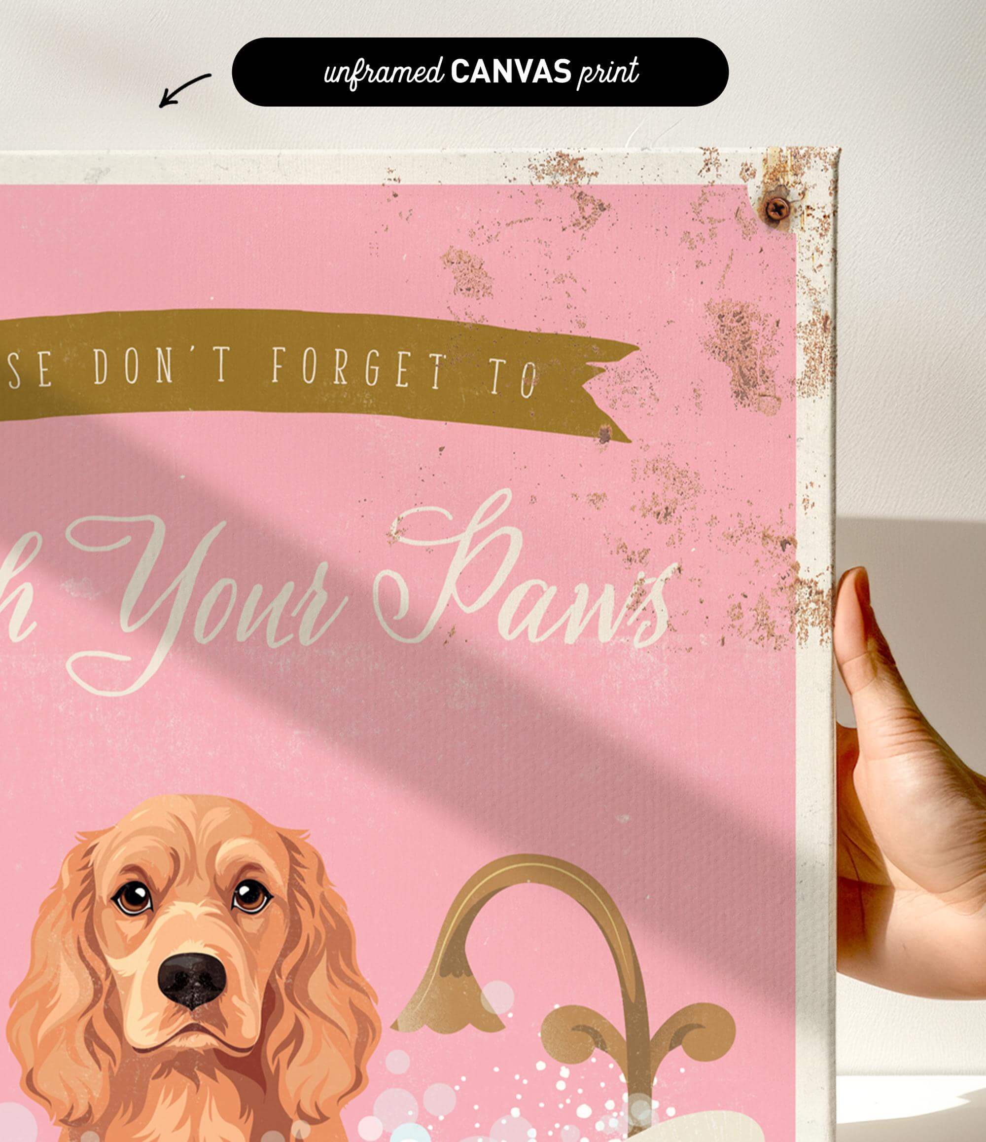 a hand holding a framed canvas print with a dog illustration on it. The text on the canvas print reads "Don't forget to wash your paws".