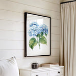 a white dresser with a framed picture of blue hydrangeas hanging on the wall above it.