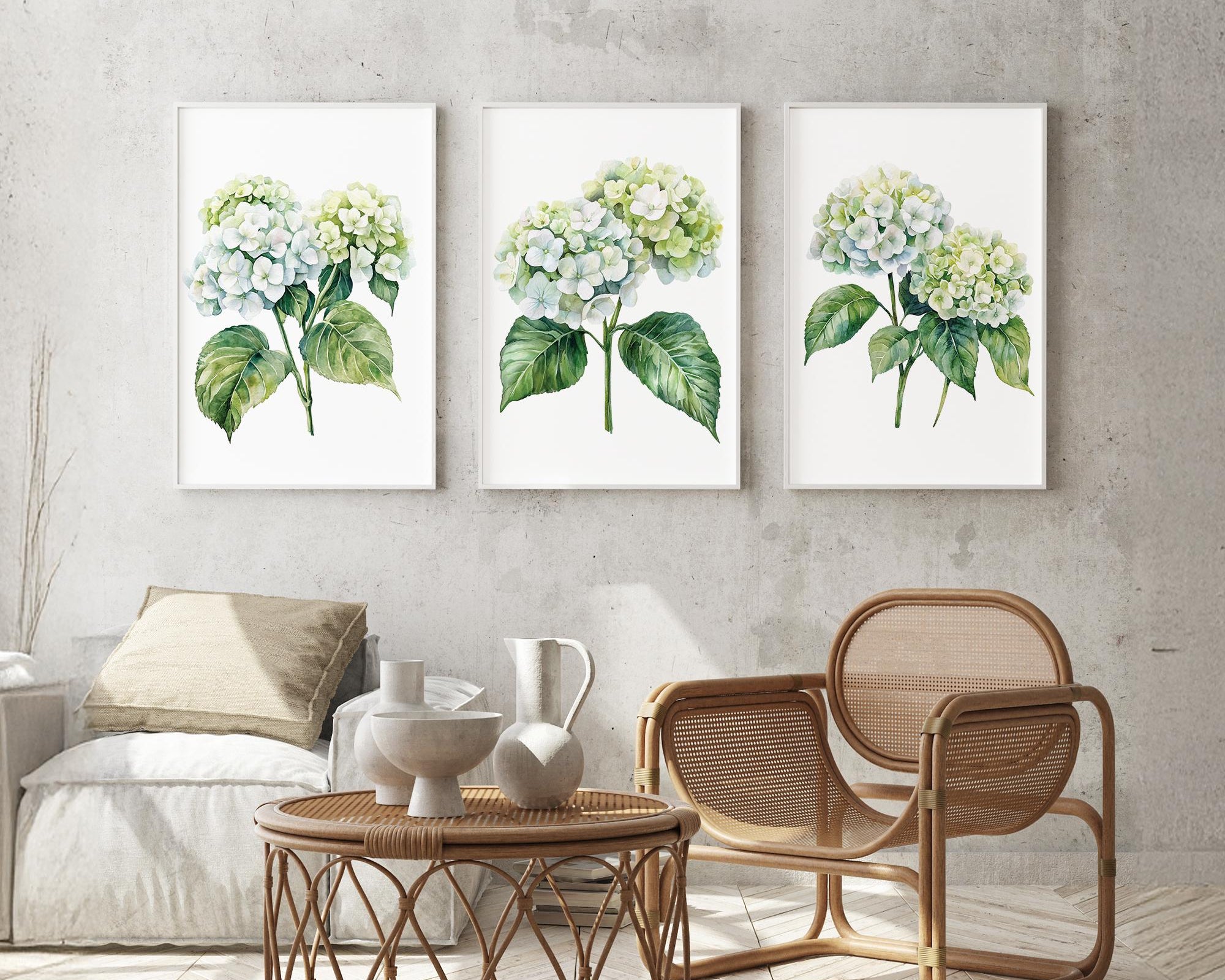 a cozy living room with a wicker coffee table, a wooden chair, and three framed watercolor paintings of white hydrangeas hanging on the wall above the seating area.