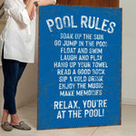 a woman standing next to a pool rules sign